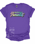 "Even My Dog Is A Feminist" printed in a pastel rainbow gradient in a vintage font on a purple t-shirt.