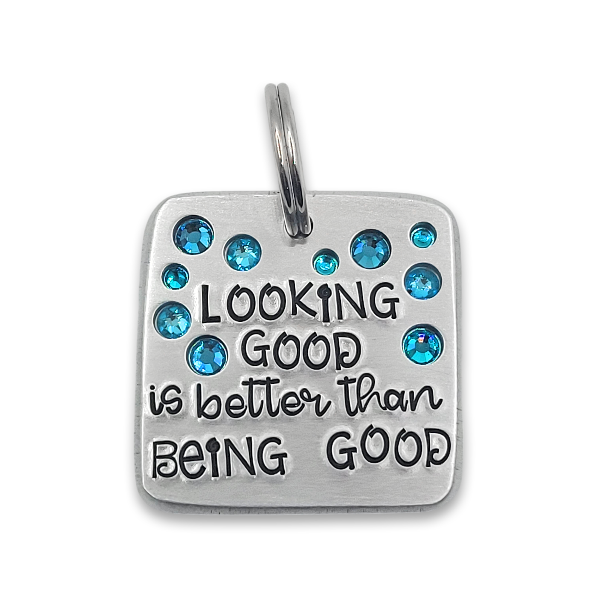A silver toned pet tag on a white background with the text "looking good is better than being good" and adorned with teal crystals.