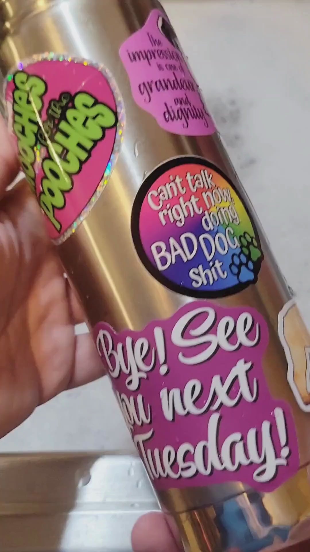 A brief video of a stainless steel water bottle with several stickers on it being submerged in water and hand washed to display the durability of stickers in water.